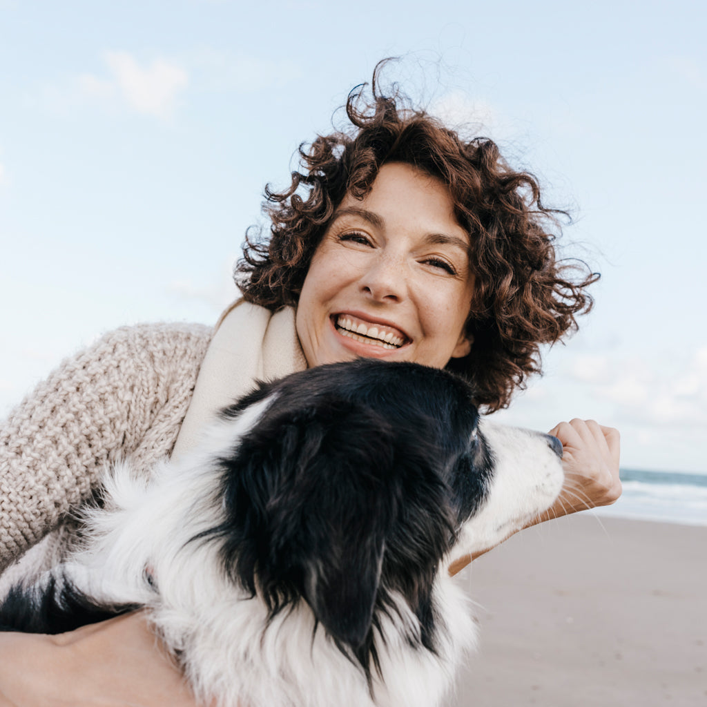 Sleep expert smiling on the beach with a dog