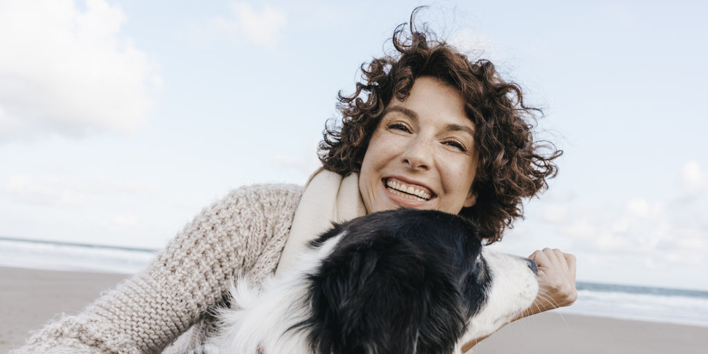 Sleep expert smiling on the beach with a dog